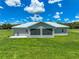 View of the rear exterior with a well-manicured lawn and screened-in patio at 35960 State Road 70 E, Myakka City, FL 34251