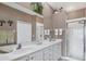 Well-lit bathroom with double sinks, white cabinets, neutral walls and a walk-in shower at 4301 Whispering Oaks Dr, North Port, FL 34287