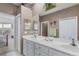 Bright bathroom featuring double sinks, a large mirror, and access to the primary bedroom at 4301 Whispering Oaks Dr, North Port, FL 34287