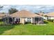 Rear view of the home featuring lanais, lawn, and mature landscaping at 4301 Whispering Oaks Dr, North Port, FL 34287