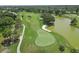 Aerial view of a vibrant green golf course with a sand trap and tranquil lake, showing off its well-maintained landscape at 454 Cerromar Rd # 174, Venice, FL 34293