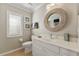 Bright bathroom featuring a white vanity, decorative mirror and a window at 5106 Pine Shadow Ln, North Port, FL 34287
