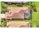 Aerial shot of a home featuring a terracotta roof, screened-in pool, and verdant landscaping at 5109 Pine Shadow Ln, North Port, FL 34287