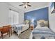 Charming bedroom featuring two twin beds, blue accent wall, and natural light from the window at 5109 Pine Shadow Ln, North Port, FL 34287