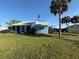 Inviting blue home with arched entry, healthy lawn, and mature palms, creating a picturesque setting at 519 Bellaire Dr, Venice, FL 34293