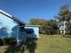 A view showing a side and back view of the blue home with a green, spacious lawn at 519 Bellaire Dr, Venice, FL 34293