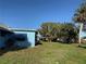 A view showing a side and back view of the blue home with a green, spacious lawn at 519 Bellaire Dr, Venice, FL 34293
