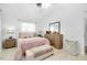 This bedroom features wood floors, a big window, a laundry basket, and a light pink bed cover at 551 Sheridan Dr, Venice, FL 34293