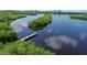 Scenic aerial view of a tranquil waterway with a dock, surrounded by mangrove islands and blue skies at 605 Cumberland Rd, Venice, FL 34293