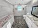 Modern bathroom featuring double vanity, walk-in shower, and stone tile flooring at 605 Cumberland Rd, Venice, FL 34293