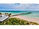 Beach view of a pier extending over turquoise waters, fringed by palm trees and vegetation at 605 Cumberland Rd, Venice, FL 34293
