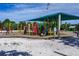 A playground with a covered seating area surrounded by a sand base and green vegetation at 605 Cumberland Rd, Venice, FL 34293