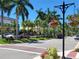 View of a quaint Venice, Florida street with flowers, palm trees, and shops in the distance at 605 Cumberland Rd, Venice, FL 34293