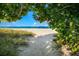 Tranquil beach view framed by leafy foliage with a wide expanse of sand meeting the ocean at 651 Percheron Cir, Nokomis, FL 34275