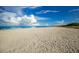 Wide beach view with pristine sand and ocean under a blue sky filled with fluffy clouds at 651 Percheron Cir, Nokomis, FL 34275