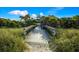 Boardwalk leads to the beach framed by lush greenery and a charming structure at 651 Percheron Cir, Nokomis, FL 34275