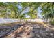 Backyard view with a white fence, trees, shade, and patchy grass at 742 Golf Dr, Venice, FL 34285