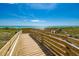 Scenic wooden boardwalk leads to a beautiful beach with clear turquoise waters and bright blue skies at 742 Golf Dr, Venice, FL 34285