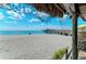 Scenic beach view with thatched umbrellas and a pier extending into the calm turquoise water at 742 Golf Dr, Venice, FL 34285