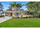 Well-maintained home with a green lawn, palm trees, and beautiful landscaping at 742 Golf Dr, Venice, FL 34285