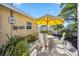 Outdoor patio with seating area and umbrella, surrounded by lush greenery at 742 Golf Dr, Venice, FL 34285