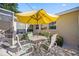 Outdoor patio area with white table and four chairs with a bright yellow sun umbrella for shade at 742 Golf Dr, Venice, FL 34285