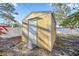 Exterior view of yellow wood shed with a white door and trim in a sunny back yard at 742 Golf Dr, Venice, FL 34285