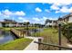 Scenic pond view featuring a wooden bridge, lush landscaping, and charming community buildings at 822 Capri Isles Blvd # 210, Venice, FL 34292