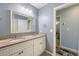Bathroom with a double sink vanity, granite countertop, framed mirror, and a doorway leading to another room at 929 The Rialto, Venice, FL 34285
