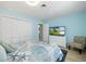 Inviting bedroom featuring blue walls, decorative bedding, and a white wicker dresser with TV at 929 The Rialto, Venice, FL 34285