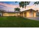 Charming one-story yellow home with an attached garage, well-manicured lawn, and lush tropical landscaping at 929 The Rialto, Venice, FL 34285