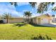 Charming single-story home with a lush green lawn, palm trees, and an attached one car garage at 929 The Rialto, Venice, FL 34285
