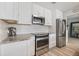 Well-lit kitchen featuring stainless steel appliances, white cabinetry, and stylish countertops at 929 The Rialto, Venice, FL 34285