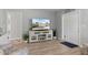 Living area features a TV on a white console with views of the front yard and door at 929 The Rialto, Venice, FL 34285