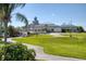 Beautiful clubhouse exterior with manicured lawn, palm trees and walking path at 945 Chickadee Dr, Venice, FL 34285