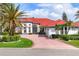 Beautiful single-Gathering home with a stunning red roof, circular brick driveway, and well-manicured landscaping at 945 Chickadee Dr, Venice, FL 34285