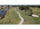 Aerial view of a scenic golf course with lush green grass, water hazards, and mature trees at 945 Chickadee Dr, Venice, FL 34285