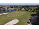 Picturesque aerial view of the golf course putting green featuring sand traps and an adjacent pond at 945 Chickadee Dr, Venice, FL 34285