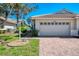 Beige single-story home with a red brick driveway and a two-car garage door at 1022 Yosemite Dr, Englewood, FL 34223