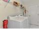 Functional laundry area with white appliances, overhead shelving, and a door to the backyard at 1022 Yosemite Dr, Englewood, FL 34223