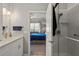 Modern bathroom featuring a glass shower, white vanity, and doorway view to the main bedroom with blue bedding at 1050 Jonah Dr, North Port, FL 34289