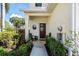 Inviting front porch featuring a dark red door, a charming round window, and lush greenery, creating a warm welcome at 1050 Jonah Dr, North Port, FL 34289