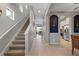 Bright hallway featuring a staircase, tiled floors, and an arched entryway leading to the kitchen, offering a seamless transition at 1050 Jonah Dr, North Port, FL 34289