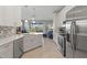 Modern kitchen featuring stainless steel appliances, white cabinetry, tiled backsplash, and seamless flow into the adjacent living area at 1050 Jonah Dr, North Port, FL 34289