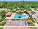Aerial view of a community pool with lounging area surrounded by palm trees and lush greenery at 1088 Bluffwood Dr, Nokomis, FL 34275