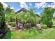 Exterior view showcasing a screened patio surrounded by vibrant green landscaping enhancing the property's curb appeal at 1088 Bluffwood Dr, Nokomis, FL 34275