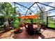 Enclosed patio area featuring an umbrella-covered table, chairs, and lush, tropical plants creating an inviting outdoor space at 1088 Bluffwood Dr, Nokomis, FL 34275
