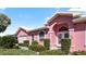 Close up of a pink home with arched windows, white trim and a well maintained lawn at 111 2Nd St, Nokomis, FL 34275