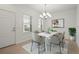 Bright dining room with modern chandelier, sleek white table, and stylish gray chairs at 11415 Fort Lauderdale Pl, Venice, FL 34293