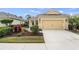 Charming yellow home featuring a two-car garage, well-manicured landscaping, and a welcoming front entrance at 11415 Fort Lauderdale Pl, Venice, FL 34293